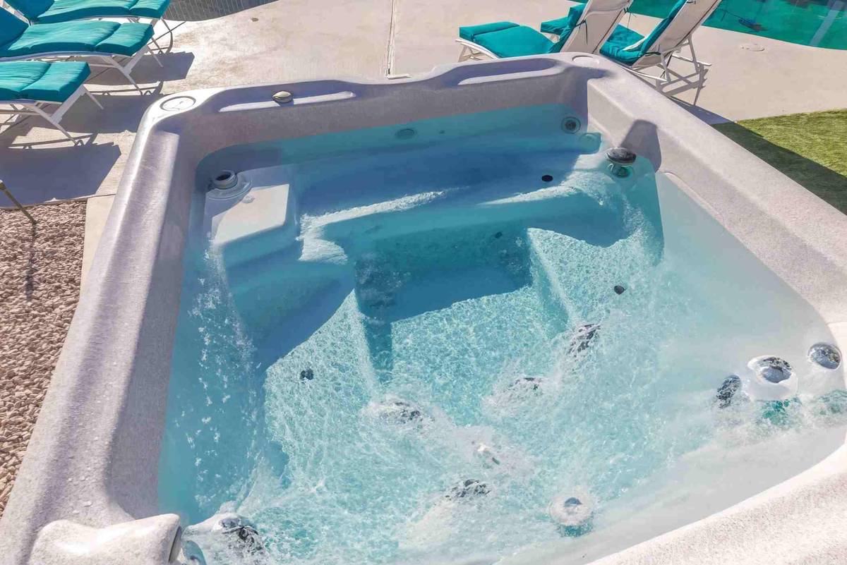 Outdoor spa with jets running beside poolside lounge chairs at Pama Lane