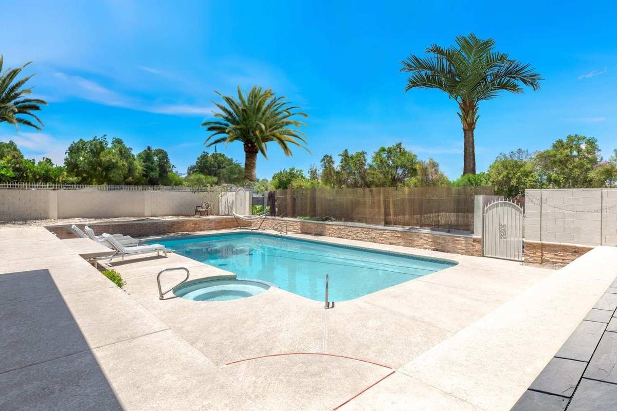 Fenced backyard pool and spa lined with palm trees at Pama Lane in Las Vegas
