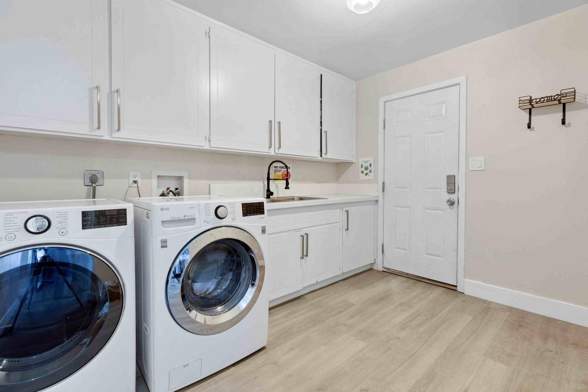 Laundry room with a washer, dryer, sink and cabinet storage at Pama Lane
