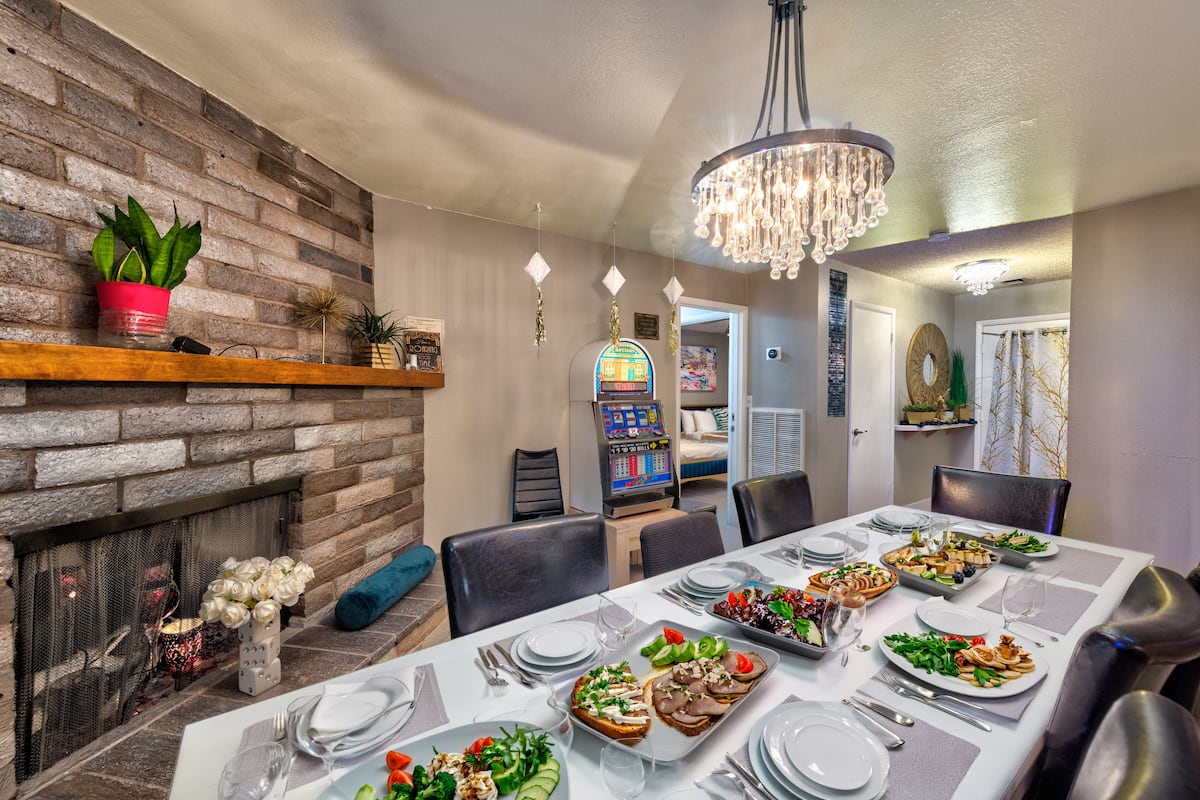 Long dining table beside a stone fireplace at Spencer Dream Estate