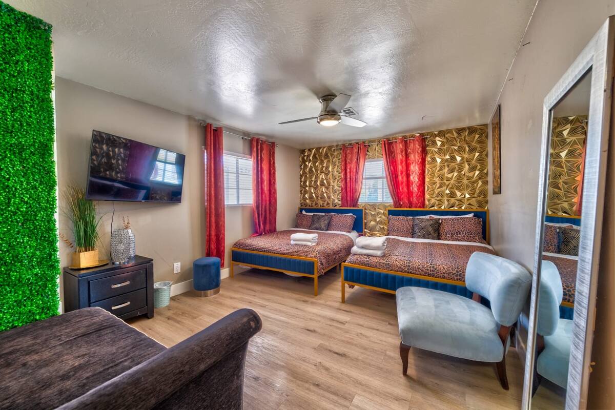 Bedroom with two beds, an armchair and a wall-mounted television at Spencer Dream Estate